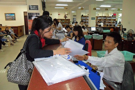 A business representative (L) making payment at the Ho Chi Minh City Social Insurance Agency (Photo: SGGP) A business representative (L) making payment at the Ho Chi Minh City Social Insurance Agency (Photo: SGGP)